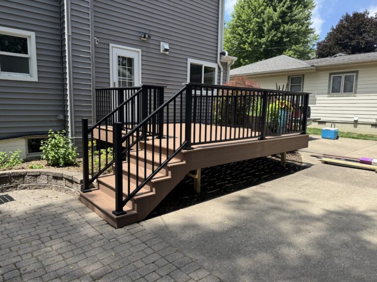 Front elevation of a composite deck renovation featuring Deckorators Summit Cliffside decking and Trex Signature railing in Historic Downtown Northville.