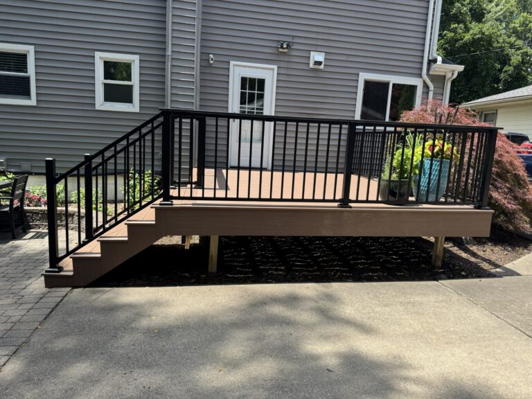 Composite deck staircase featuring Trex Signature black aluminum railing and Deckorators Summit Cliffside decking in Historic Downtown Northville.