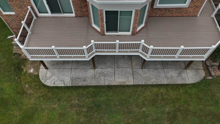 Close overhead view of Deckorators Summit Cliffside decking, AZEK fascia, and white Trex Select railing with black balusters.