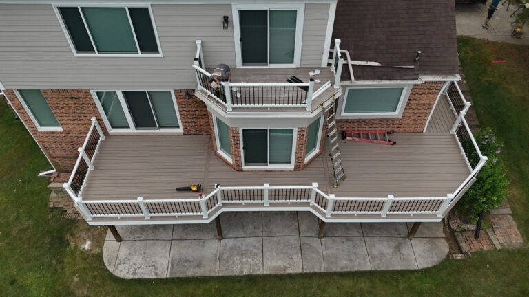 Upper balcony and main deck finished in Deckorators Summit Cliffside with white Trex Select railing and black balusters.